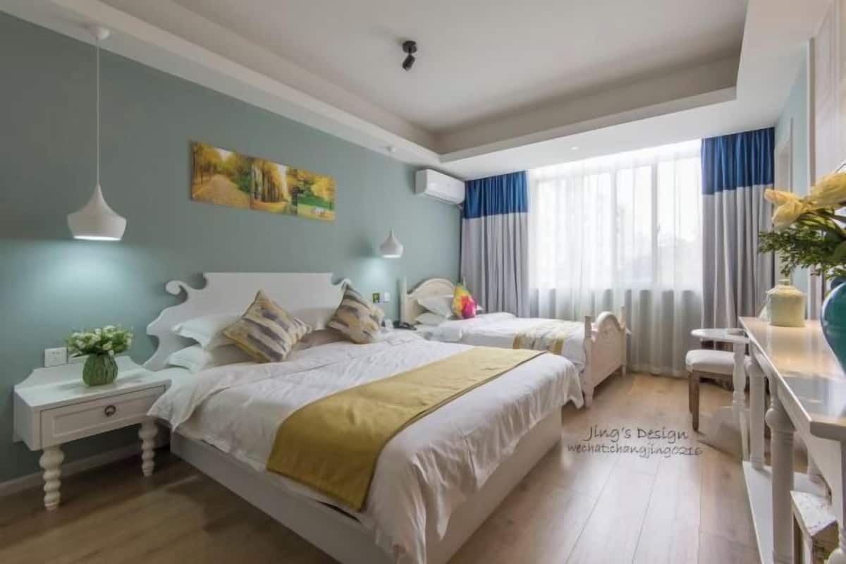 Un dormitorio con dos camas, una mesita de noche, una ventana con cortinas y un cuadro en la pared.