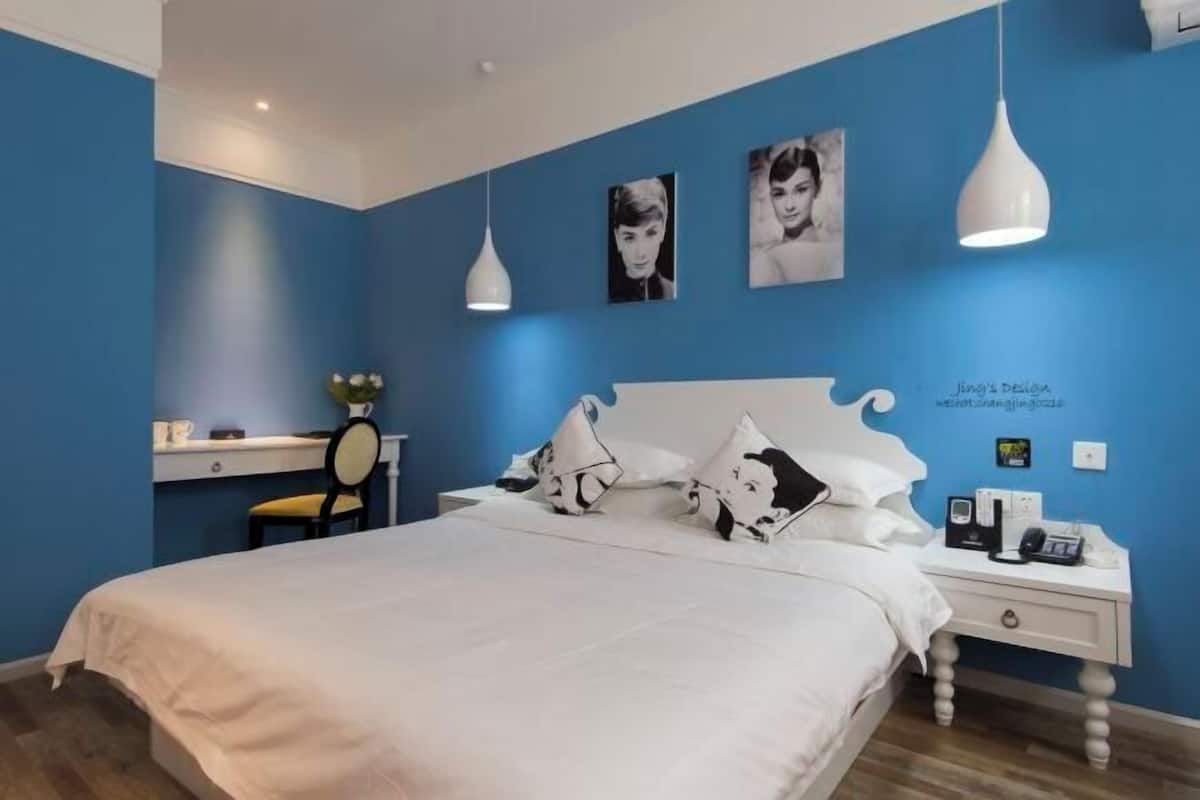 Un dormitorio con cama, mesita de noche, lámpara y decoración en la pared.