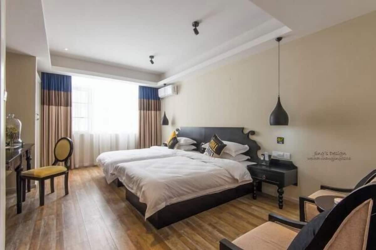 Habitación de hotel con dos camas, un escritorio, una silla y una lámpara colgante.