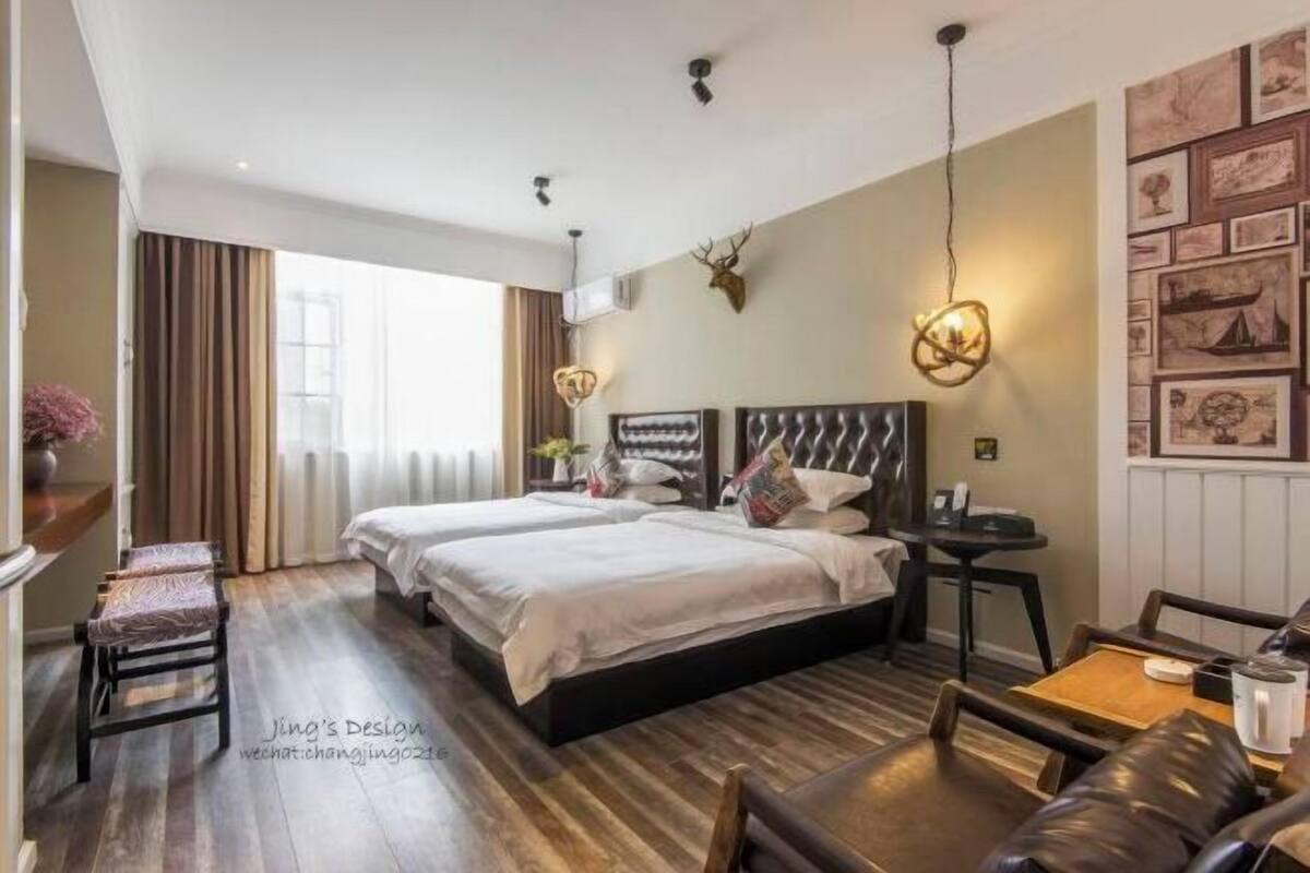 Una habitación de hotel con dos camas, una mesita, una silla y un adorno en la pared.