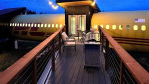 Une terrasse avec coin salon extérieur et barbecue, offrant une vue sur un grand avion.