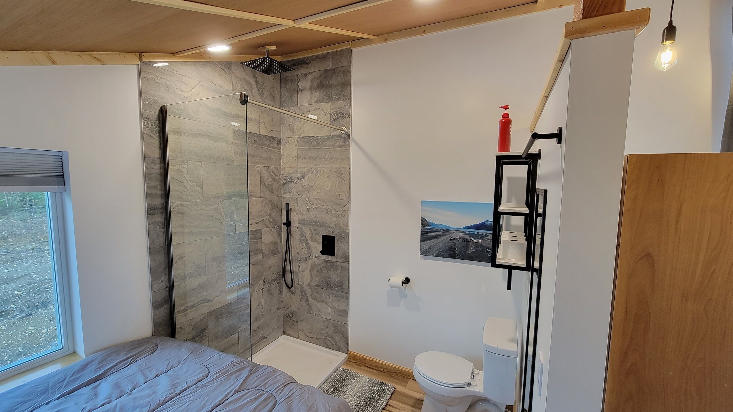 Ein modernes Badezimmer mit Duschkabine aus Glas, Toilette und Ablagefläche für Pflegeprodukte.