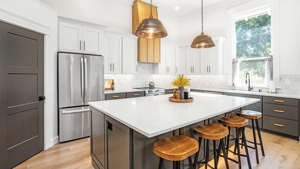 Una cocina moderna con una isla grande, electrodomésticos de acero inoxidable e iluminación colgante.