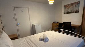 A hotel room with a bed, a desk, a chair, a wardrobe, and a door. - Curzon St - 4 Beds, Sleeps 7 with Street Parking (Reading)
