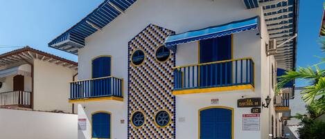 Un edificio con fachada a cuadros, balcones y un letrero que indica la dirección.