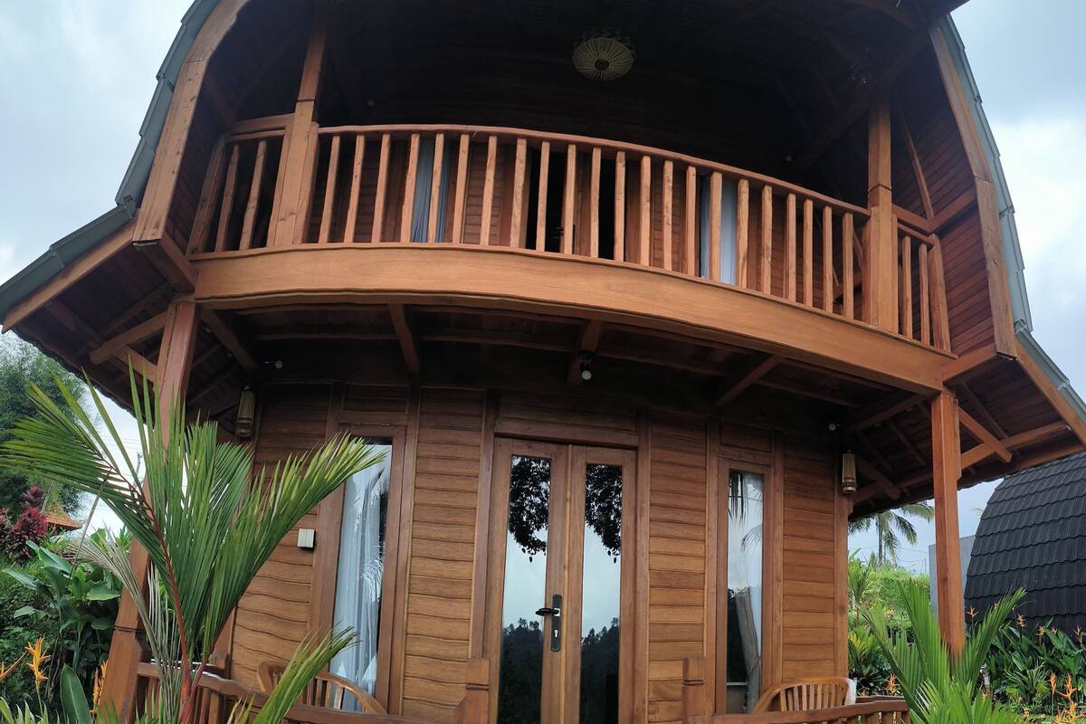 A wooden multi-level house with a balcony, large windows, and a door.