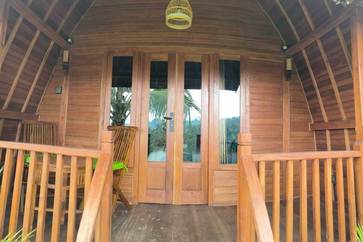 A wooden cabin with a porch, a door, and a hanging light fixture.