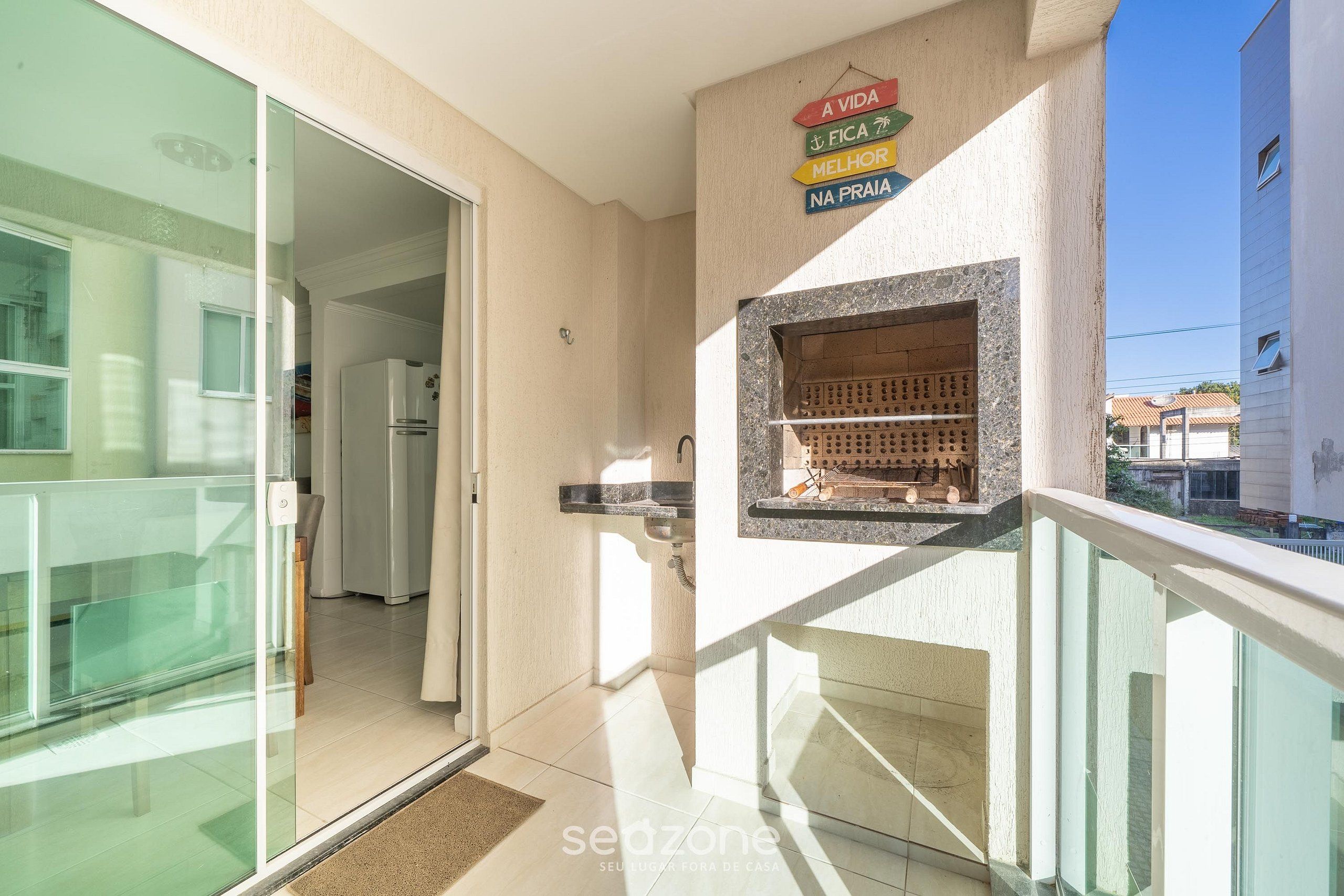 Una cocina moderna con una parrilla empotrada, una puerta de cristal que da a un balcón y un cartel con texto en portugués.