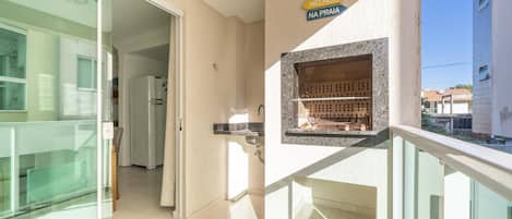 Una cocina moderna con una parrilla empotrada, una puerta de cristal que da a un balcón y un cartel con texto en portugués.