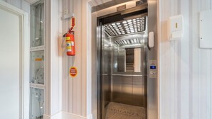 An elevator with a metallic interior, a fire extinguisher mounted on the wall, and a doormat with the name "AFALANTA RESIDENCE". - 2-bed Apt w/ BBQ - Downtown Bombinhas Caa103 (Bombinhas)