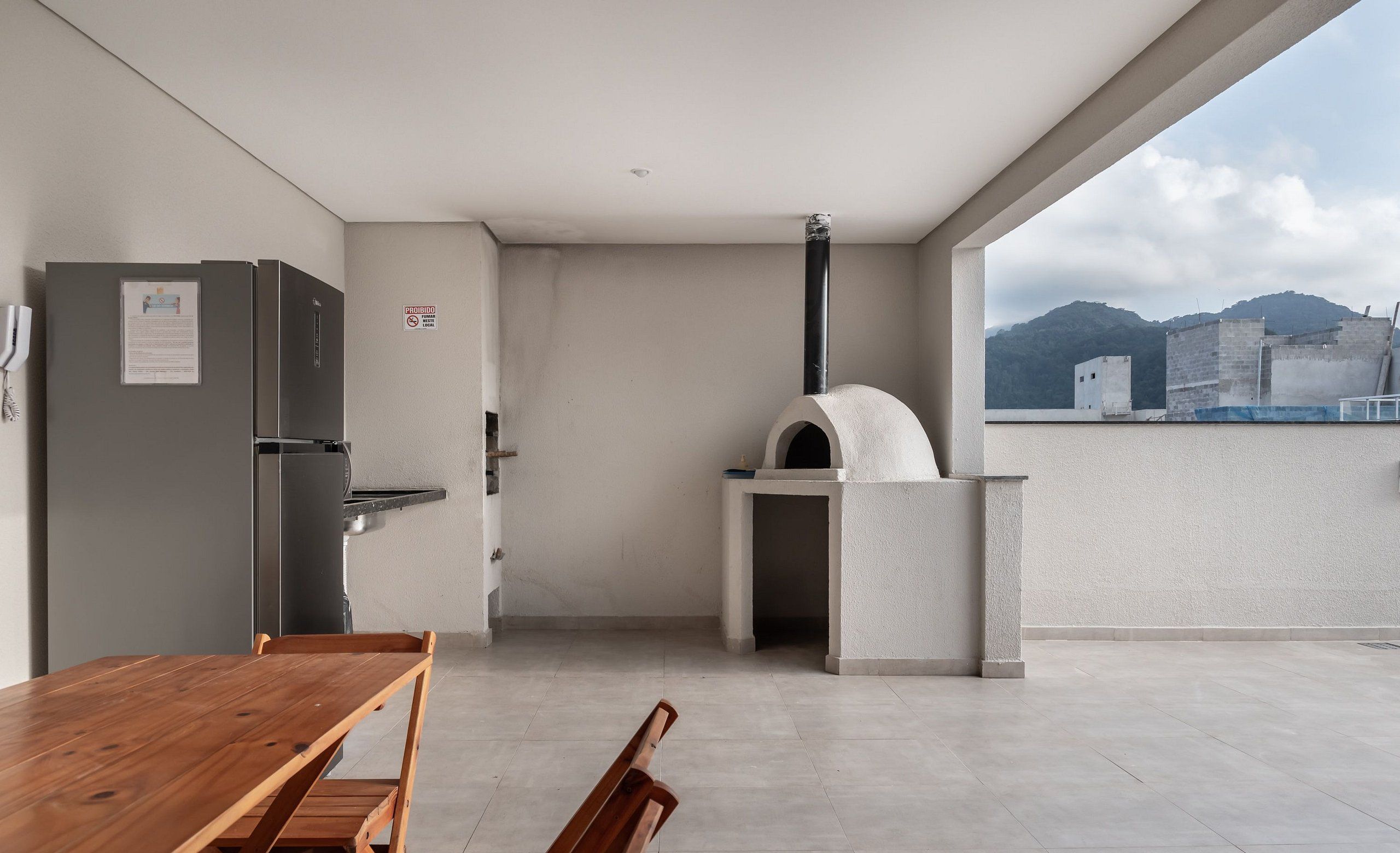 A modern kitchen with a built-in oven and a dining area with a wooden table and benches.