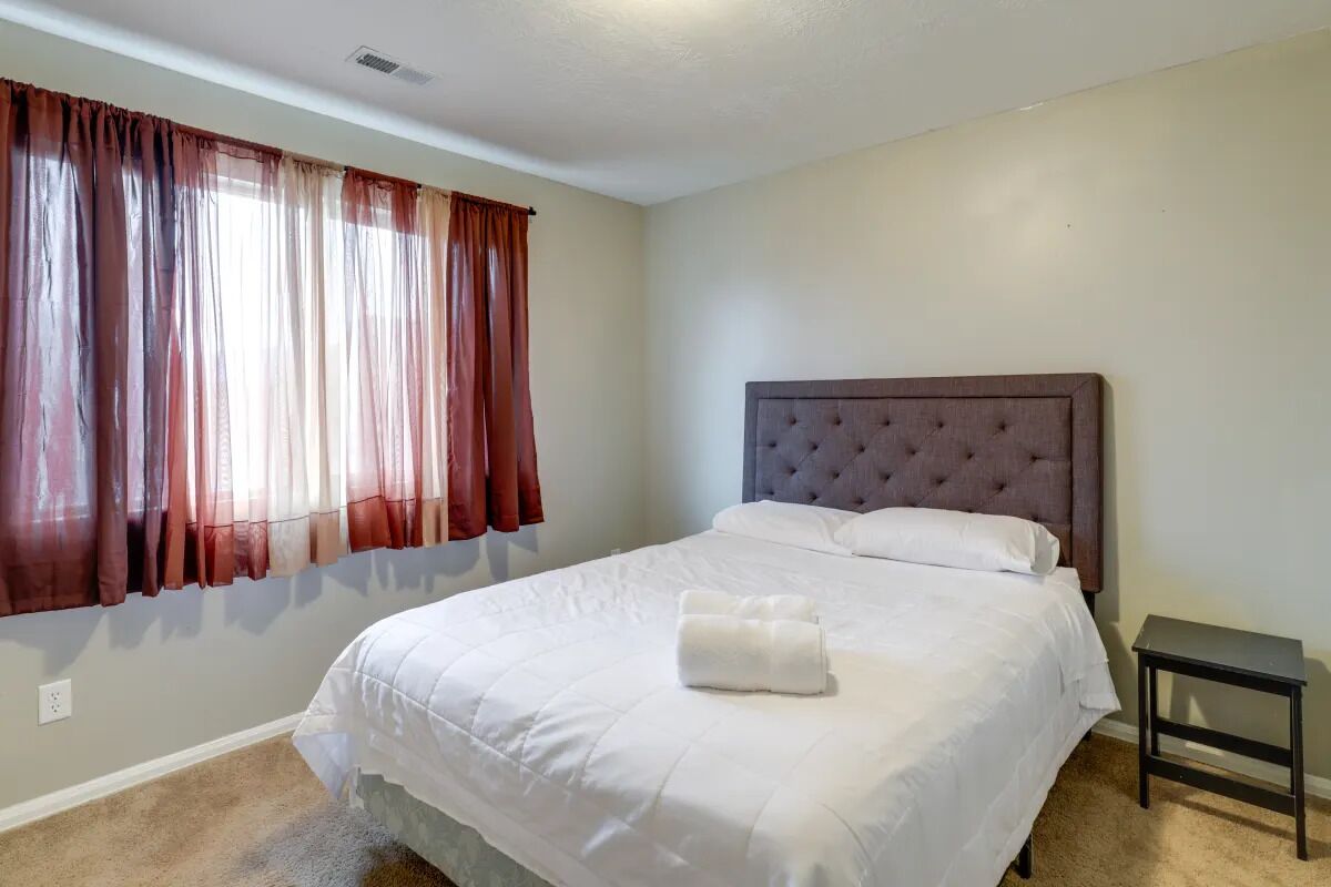 A bedroom with a large bed, a headboard, and a nightstand.