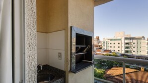 A balcony with a stone wall, a sink, and a small outdoor grill.