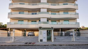 A multi-story building with a white facade, balconies, and a gated entrance.