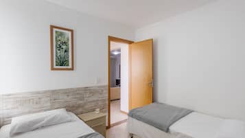 Un dormitorio con dos camas, una puerta de madera, un cuadro enmarcado en la pared y un cabecero de baldosas.
