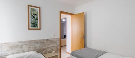 Un dormitorio con dos camas, una puerta de madera, un cuadro enmarcado en la pared y un cabecero de baldosas.