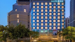 A modern hotel with a prominent circular structure on the left and a grid of illuminated windows on the right. - DIOTEL (Shantou)