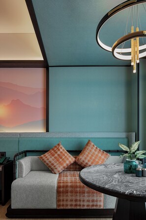 En moderne stue med sofa, rundt bord og en hængende lampe.