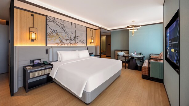 A modern hotel room with a large bed, bedside tables, a desk, and a TV. - DIOTEL (Shantou)