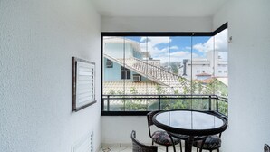 A balcony with a glass door, a round table with chairs, and a framed picture on the wall. - 3BR apt W/bbq 240m sea Bombas/sc Cay0123 (Bombinhas)
