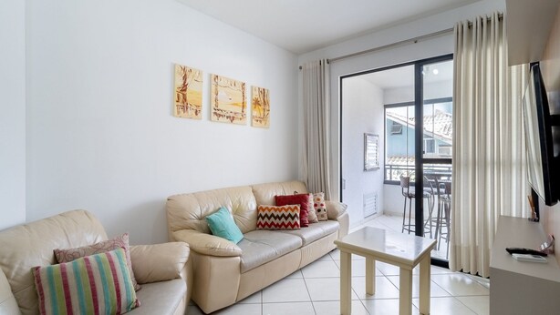 A living room with a beige leather sofa, a small wooden table, and a balcony with a view. - 3BR apt W/bbq 240m sea Bombas/sc Cay0123 (Bombinhas)