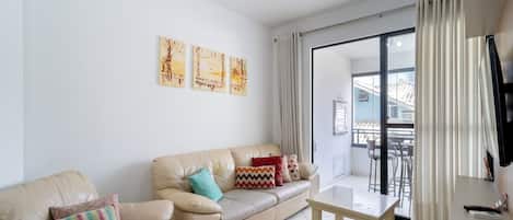 Un salón con un sofá de cuero color beige, una mesita de madera y un balcón con vistas.