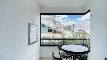 A balcony with a glass door, a round table with chairs, and a framed picture on the wall.