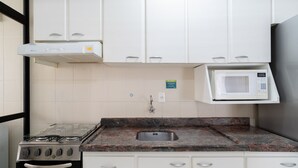 A kitchen with white cabinets, a gas stove, a microwave, and a stainless steel sink. - 3BR apt W/bbq 240m sea Bombas/sc Cay0123 (Bombinhas)