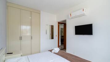 Ein Schlafzimmer mit Bett, Kleiderschrank, Fernseher und Klimaanlage.