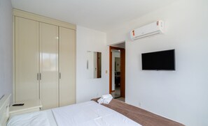 A bedroom with a bed, a wardrobe, a television, and an air conditioning unit. - 3BR apt W/bbq 240m sea Bombas/sc Cay0123 (Bombinhas)