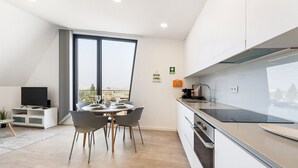 Una cucina moderna con un'ampia finestra, un'area pranzo con tavolo imbandito per quattro persone e una televisione a schermo piatto nell'angolo.