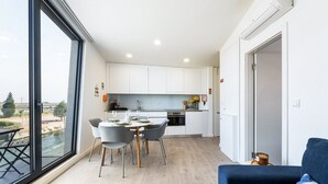 Una cucina moderna con mobili bianchi, un tavolo da pranzo con sedie e una vista panoramica attraverso ampie finestre.