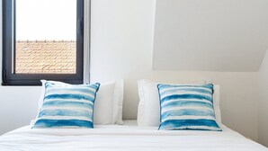 Un letto con biancheria bianca e due cuscini a righe blu.