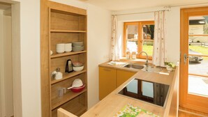 A compact kitchen with wooden shelves, a sink, and a window with curtains. - Apartment Typ C by Interhome (Längenfeld)