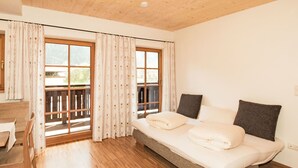 A bedroom with a bed, wooden flooring, and large windows with curtains. - Apartment Typ C by Interhome (Längenfeld)