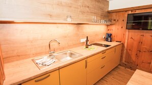 A kitchen with wooden cabinets, a stainless steel sink, and a coffee maker on the countertop. - Apartment Typ A by Interhome (Längenfeld)