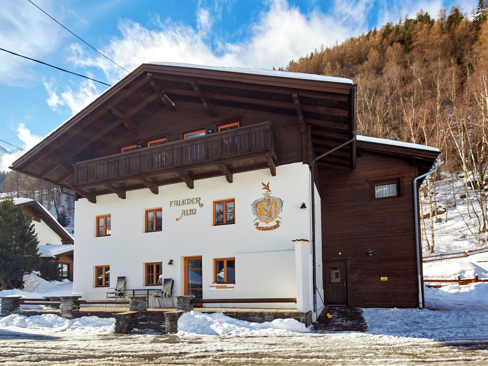 Un bâtiment à la façade blanche et aux balcons en bois, appelé « Falkner Alm ».