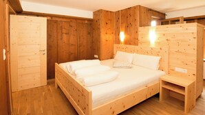 A wooden bedroom with a bed, bedside tables, and a wardrobe. - Apartment Typ A by Interhome (Längenfeld)