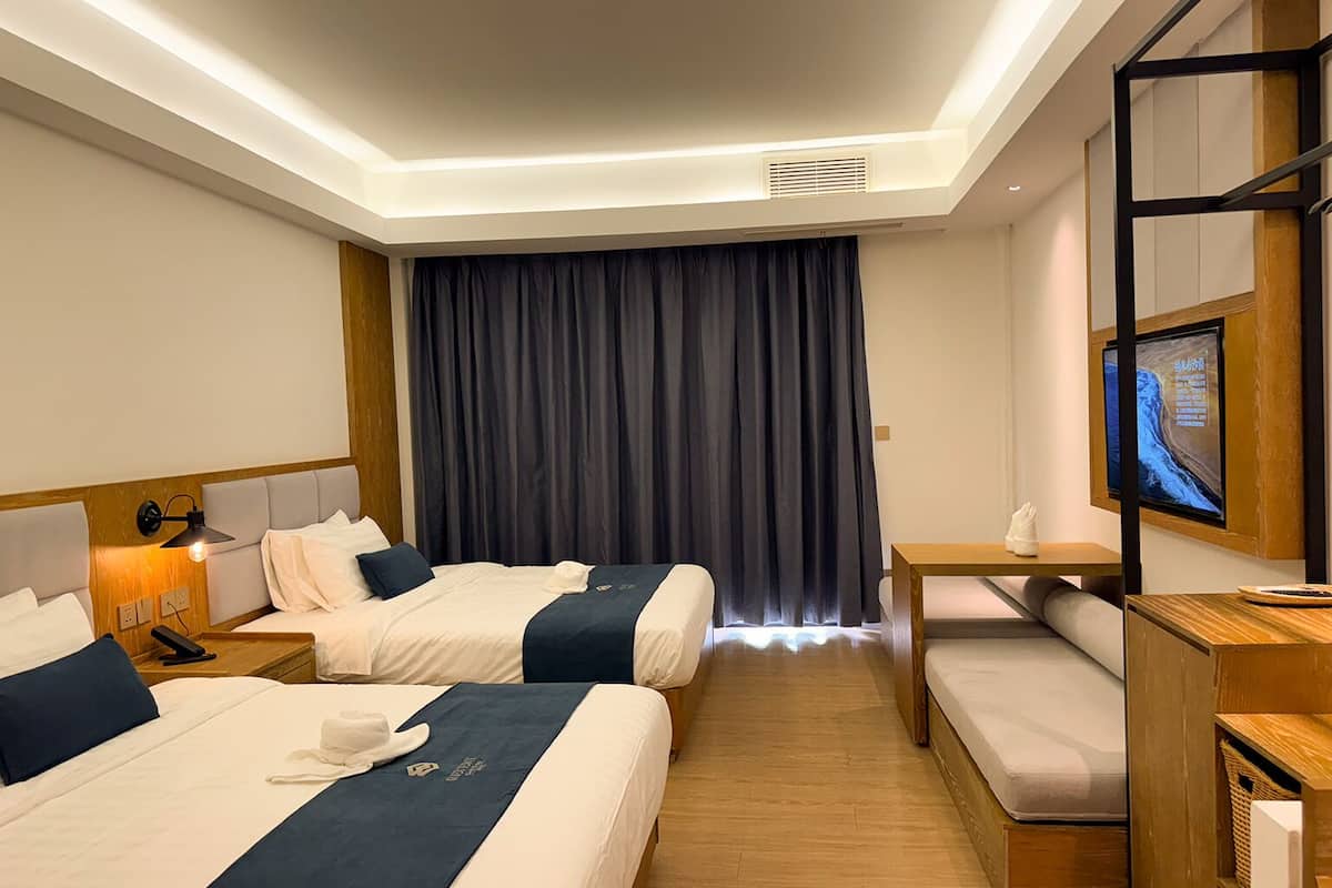 Una habitación de hotel con dos camas, un escritorio, un televisor y un sofá.