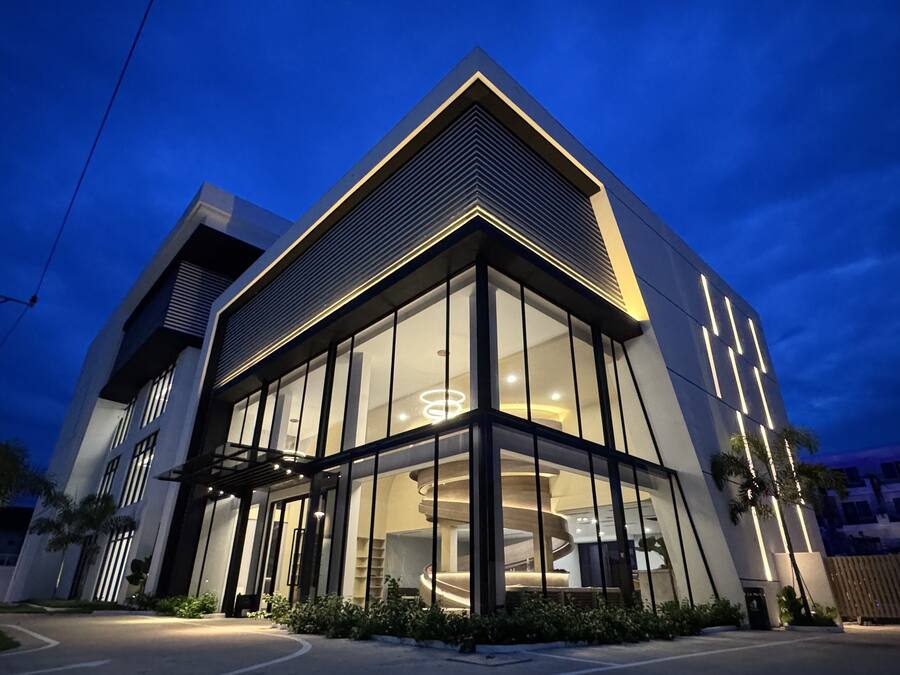 Un edificio moderno con grandes ventanales, una entrada destacada y un tragaluz circular.