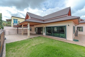 Une maison moderne dotée d’un patio couvert, de grandes fenêtres et d’une pelouse bien entretenue.
