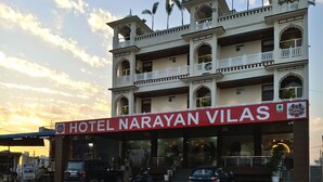 Un hôtel appelé Hotel Narayan Vilas, doté d’un style architectural traditionnel, avec de nombreux balcons et une entrée imposante.