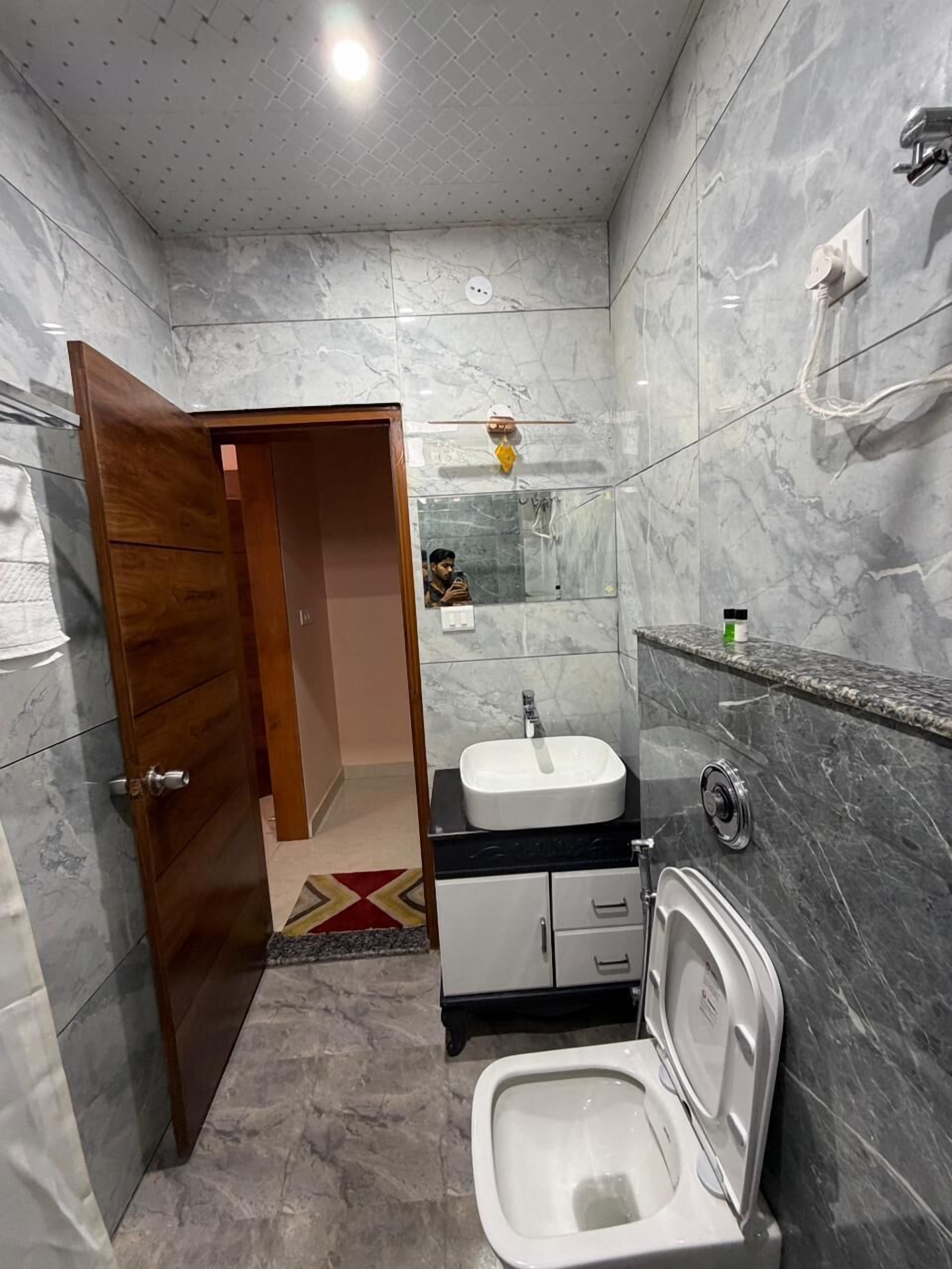 A bathroom with a marble floor, a white sink, a toilet, and a shower.