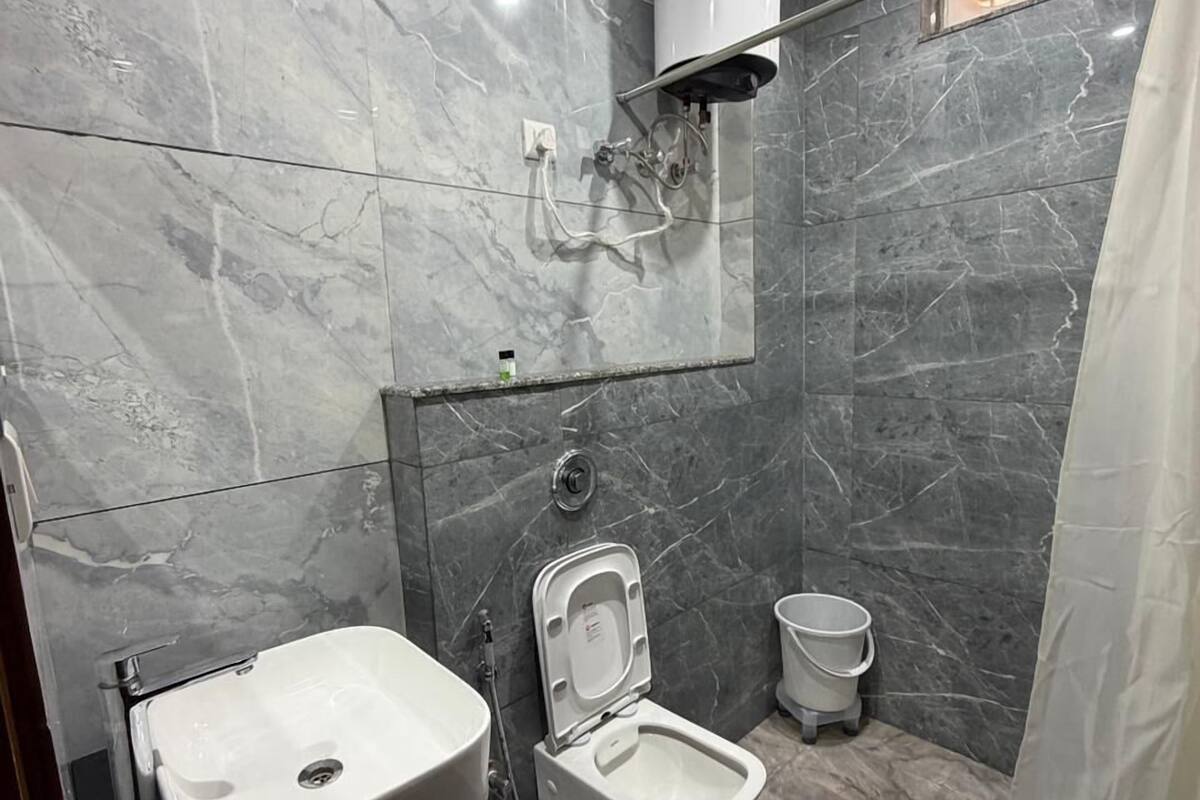 Une salle de bain moderne avec un sol en marbre, un lavabo blanc, un bidet et un rideau de douche.