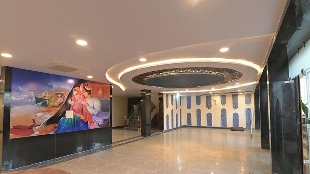 Un hall d’entrée spacieux, orné d’une grande fresque murale, avec un escalier et un design de plafond moderne.