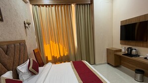 Une chambre d’hôtel équipée d’un lit, d’un ventilateur de plafond, d’une télévision et d’une petite kitchenette.