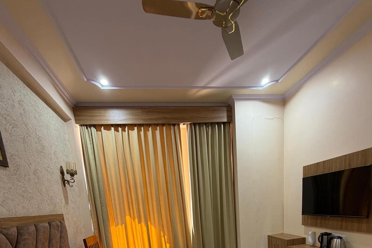 Une chambre d’hôtel équipée d’un lit, d’un ventilateur de plafond, d’une télévision et d’une petite kitchenette.