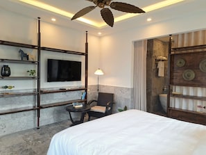 Une chambre d’hôtel moderne dotée d’un grand lit, d’un téléviseur fixé au mur, d’un bureau avec une chaise et d’un ventilateur de plafond.
