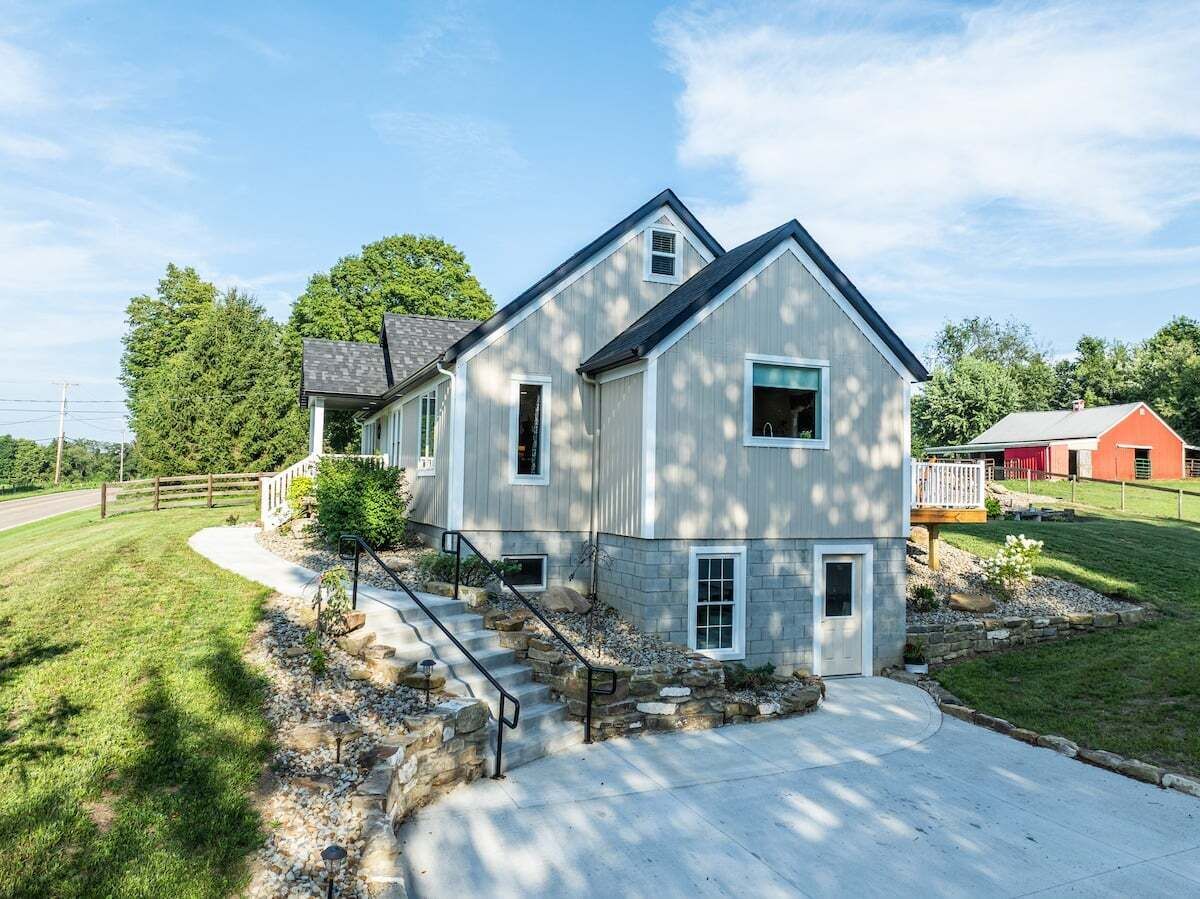 A two-story house with a front porch, stone steps, and a driveway.