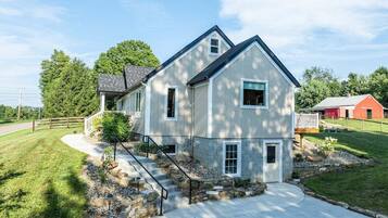 A two-story house with a front porch, stone steps, and a driveway.